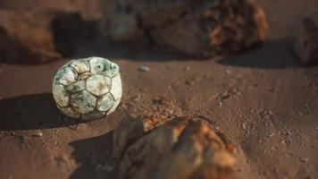 bola de futebol velha na praia de areia