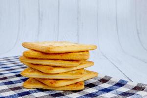 Cracker squares stacked, Cracker squares stacked on plaid fabric, Cracker squares stacked on white wood background photo