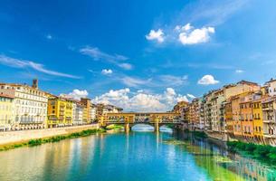 Ponte Vecchio stone bridge with colourful buildings houses over Arno River blue turquoise water photo