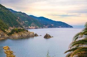 Aerial top panoramic view of green hills, rocks, cliffs and Gulf of Genoa at sunset dusk, Ligurian Sea photo