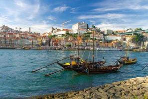 portugal, paisaje de la ciudad de porto, un grupo de botes de madera amarillos con barriles de vino en el río douro foto