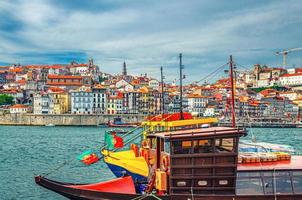 Traditional wine boats in water of Douro River and Ribeira district embankment with colorful buildings photo
