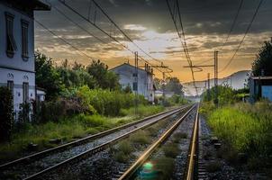 Railway tracks with old buildings on sides, wires above and Tuscany hills and mountains photo