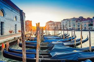 Gondolas moored docked on pier of Grand Canal waterway in Venice photo