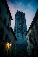 Bell tower of Chiesa di San Frediano catholic church view through narrow street with lamp photo
