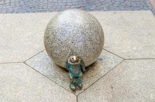 Wroclaw, Polonia, 7 de mayo de 2019, el enano está empujando una bola de mármol, el famoso gnomo en miniatura de bronce foto