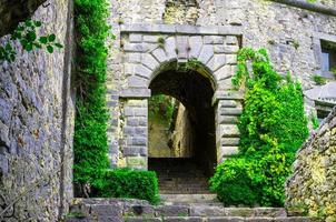 Stone walls, arches, stairs, lamp and green dangling plants of ancient Castello Doria castle tower in Portovenere photo