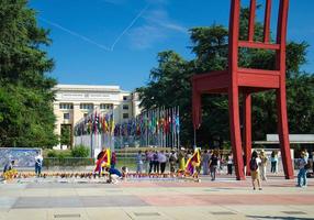 Broken chair on the square of Nations and walking people in front of Palace of United nations building photo