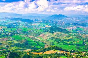Aerial top panoramic view of landscape with valley, green hills, fields and villages of Republic San Marino photo