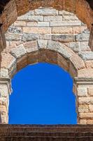 cielo azul claro a través de la ventana de arco de ladrillo de piedra caliza de la arena de verona