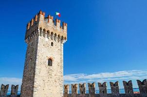 Tower with italian flag and stone defense wall with merlons of Scaligero Castle Castello di Sirmione photo