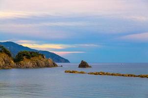 Aerial top panoramic view of green hills, rocks, cliffs and Gulf of Genoa at sunset dusk photo