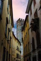 campanario de la iglesia católica chiesa di san frediano vista a través de una calle angosta en el centro histórico foto