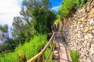 sendero peatonal de piedra con barandilla entre los pueblos de corniglia y vernazza foto