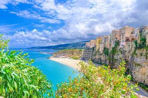 Tropea town and beach, Tyrrhenian Sea turquoise water, colorful buildings on top of high big rocks cliffs photo