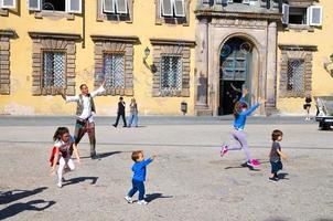 Lucca, Italy man is blowing colorful soap bubbles and playing with small young children photo