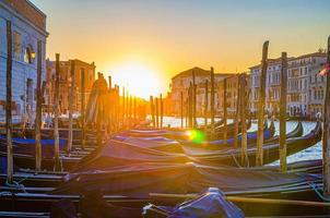 Gondolas moored docked on pier of Grand Canal waterway in Venice photo