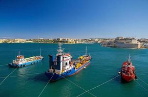 Three colourful cargo ships in harbour Valletta, Malta