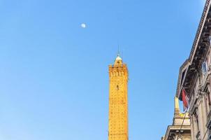 parte superior de la torre medieval garisenda de bolonia y luna con fondo de cielo azul foto