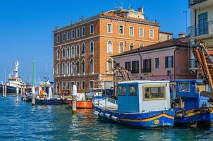 Boats and fishing industrial ships moored in water canal and old buildings on embankment in Chioggia photo