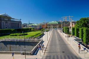 Riksplan green grass lawn, bushes and street with national flags on Sodermalm island photo