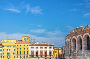 The Verona Arena limestone walls with arch windows and old colorful multicolored buildings photo
