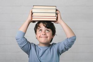 niño feliz con libros en la cabeza foto