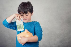 niño feliz ahorrando dinero en una alcancía foto