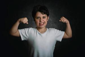 niño fuerte mostrando los músculos de sus brazos foto