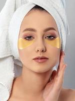 Woman applying golden hygrogel eye patches