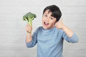 Happy child with broccoli in his hand photo