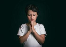 niño con las manos juntas orando foto