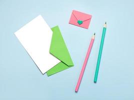 green paper envelope with white card, pink paper envelope pink and green pencils