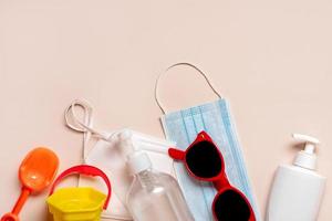 Protective surgical mask, protection mask ffp2 KN95 with sunglasses,beach bucket and plastic bottle of sunscreen.Summer concept with covid-19 photo