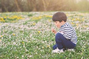 niño feliz con flores en primavera foto