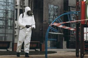 Cleaning and Disinfection on the playground in the sity complex amid the coronavirus epidemic Teams for disinfection efforts Infection prevention and control of epidemic Protective suit and mask photo
