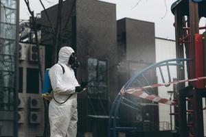 Cleaning and Disinfection on the playground in the sity complex amid the coronavirus epidemic Teams for disinfection efforts Infection prevention and control of epidemic Protective suit and mask photo