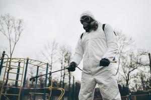 Cleaning and Disinfection on the playground in the sity complex amid the coronavirus epidemic Teams for disinfection efforts Infection prevention and control of epidemic Protective suit and mask photo