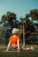 Beautiful blonde doing stretching on the lawn of a football field photo