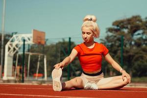 young beautiful girl doing warm-up before sports exercise at school stadium photo