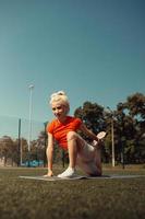 hermosa rubia haciendo estiramientos en el césped de un campo de fútbol foto