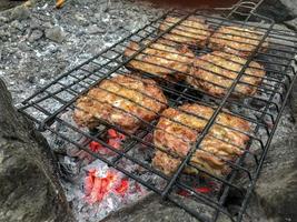 Forest barbecue grilled food on fire, delicious cooking in campfire, barbecue grilled kororec on fire photo