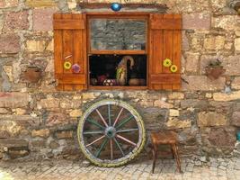 Antique window detail and wheel, chair and wheel in front of antique building facade photo