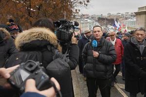 Moscow, Russia - February 24, 2019. Nemtsov memorial march. Foreign journalist with a microphone is reporting from the scene to the digital camera photo