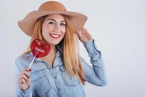 Portrait of smiling Young woman with heart shaped lollipop photo