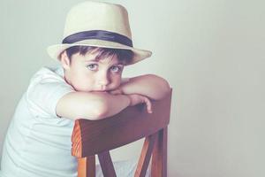 niño triste sentado en una silla foto