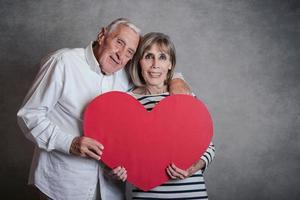 Portrait of happy senior couple with a red heart photo