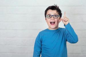 chico con gafas apuntando con el dedo hacia arriba foto