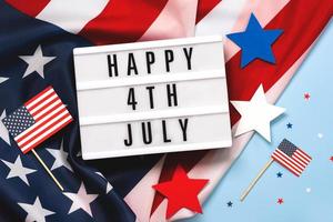 feliz día de la independencia 4 de julio. caja de luz con el texto feliz 4 de julio, banderas americanas y estrellas foto