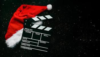 Movie clapperboard with Santa's hat and sparkling glitter with space for text. Christmas movies concept photo